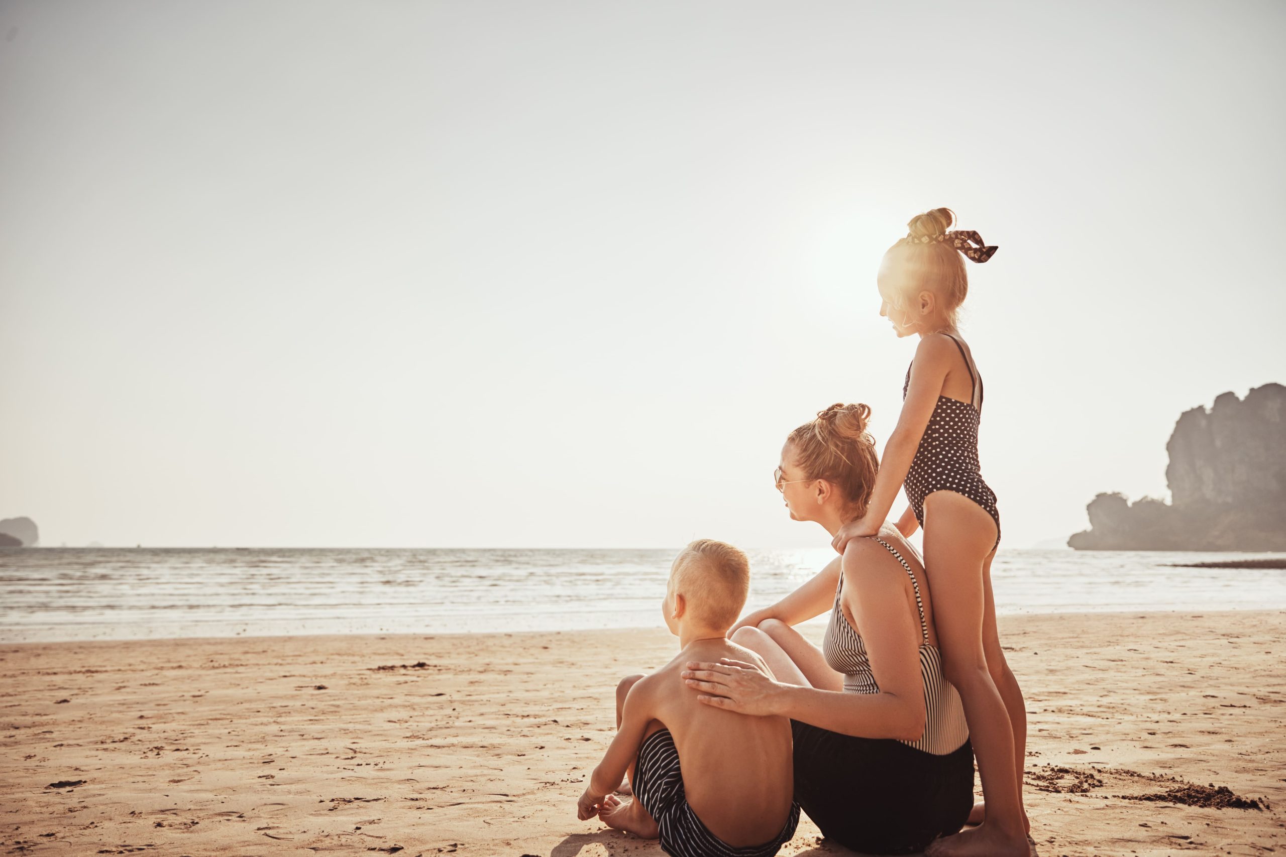 Family looking at the sunset in the beach.