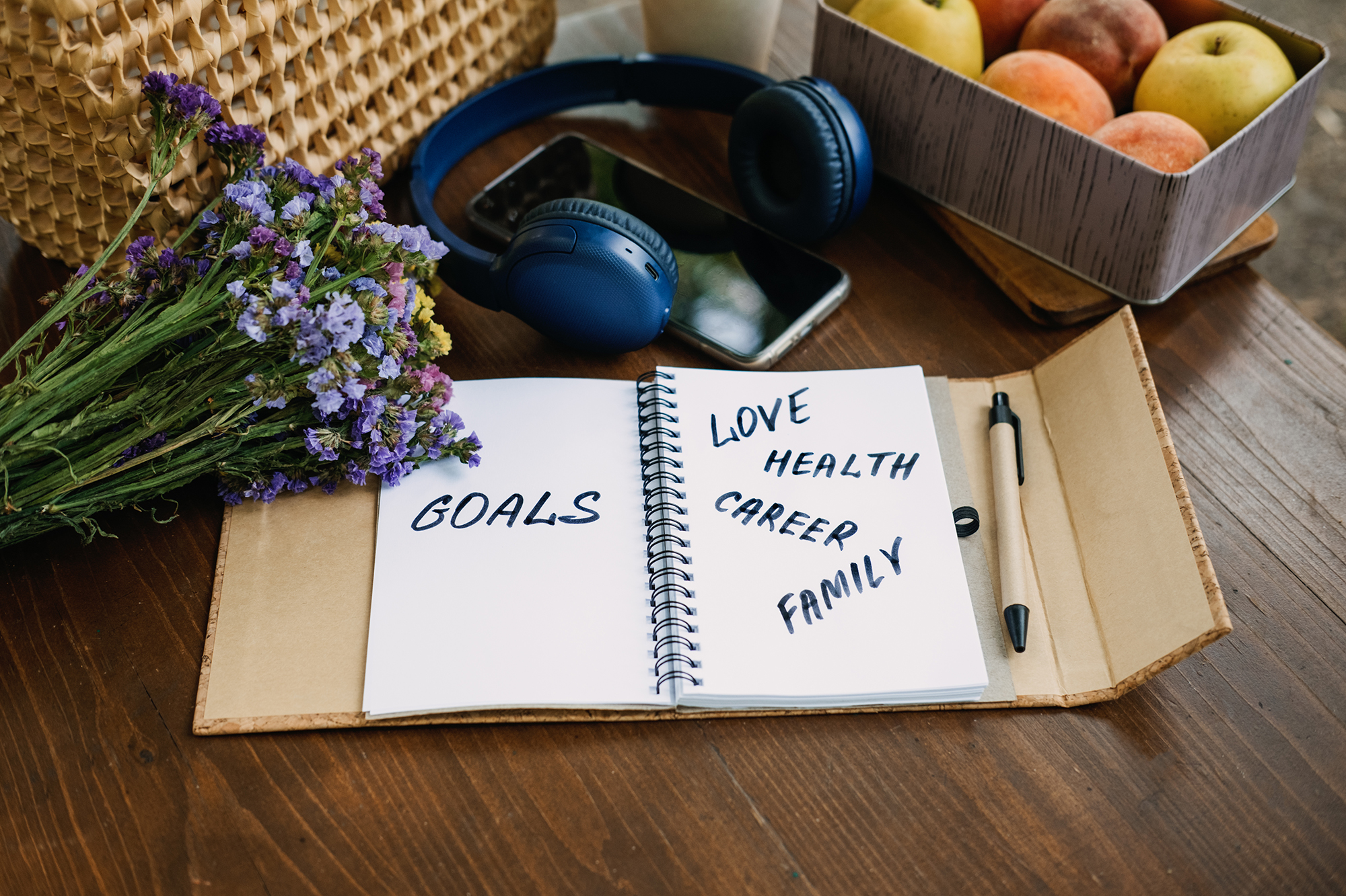 Open notebook on a table with New Year’s resolutions, goals, and a motivational phrase written inside, symbolising planning for health and wellbeing